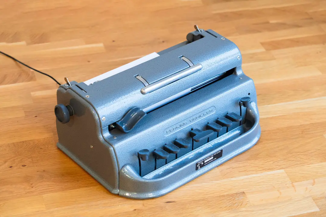 Braille writer with a USB cable sitting on a desk.