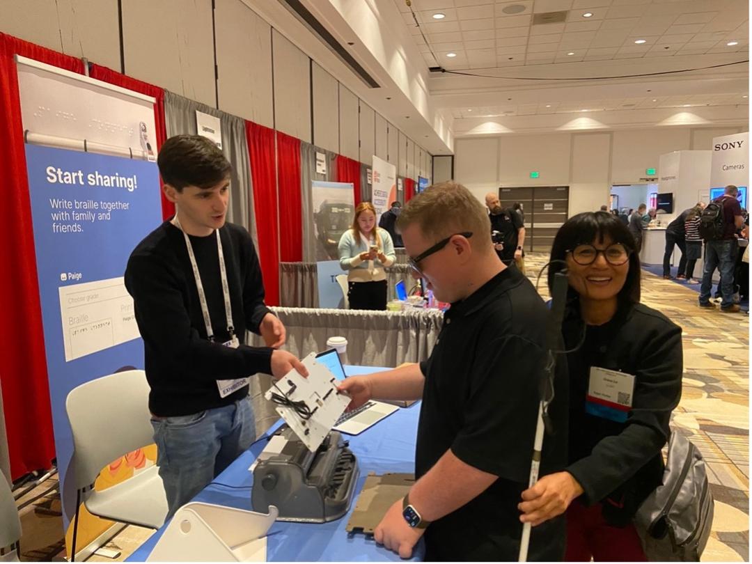 Gregory demonstrating Paige Connect to a QTVI and their student at the 2024 CSUN