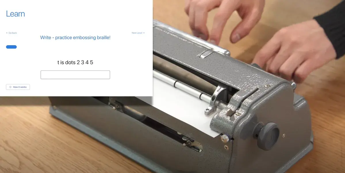 Hands using a classic braille writer upgraded with Paige Connect, while a learning software screen overlay guides the user to emboss braille letters.