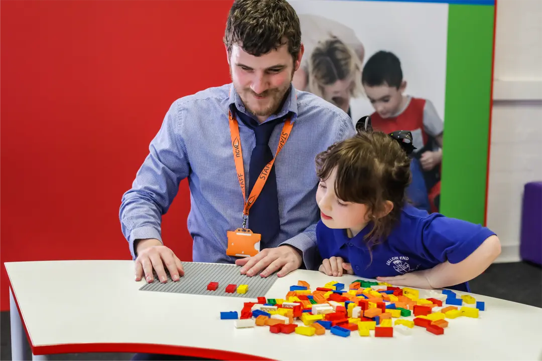 Shows New College Worcester teacher, Sean Randall, and a young student playing with LEGO Braille Bricks.