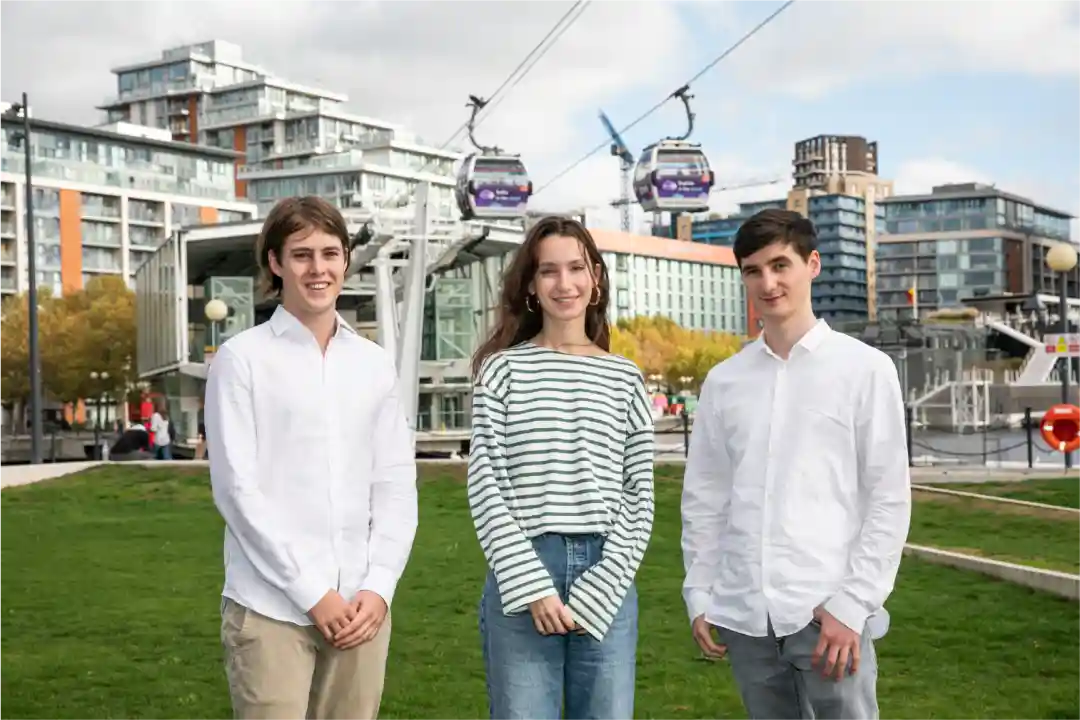 Members of the Paige team (left to right, Sergio Gosalvez, Nina Moutonnet, Gregory Hargraves) standing outside City Hall, London, Newham. In the background is the London cable car and Royal Docks waterfront.
