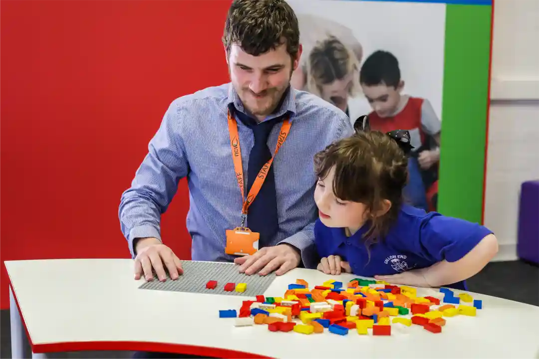 Shows New College Worcester teacher, Sean Randall, and a young student playing with LEGO Braille Bricks. 